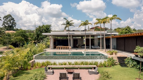 Casa ganha vasto jardim com lago artificial, piscina e quadra de areia