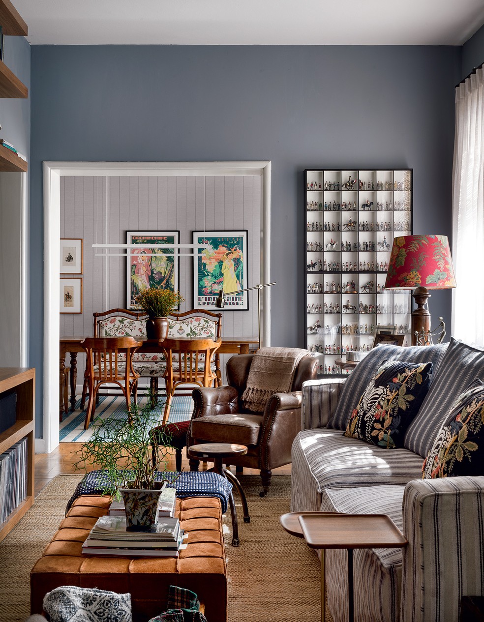 SALA | O sofá existente foi repaginado com tecido da Officina Design, que forneceu também a estampa floral do banco em faux bambou — técnica popular na França do século 19 —, que quebra a lógica das cadeiras ao redor da mesa de jantar. Ao fundo, as paredes da sala de jantar receberam tecido autocolante de Anna Milliet e quadros adquiridos em Saigon, Vietnã — Foto: Romulo Fialdini/Divulgação