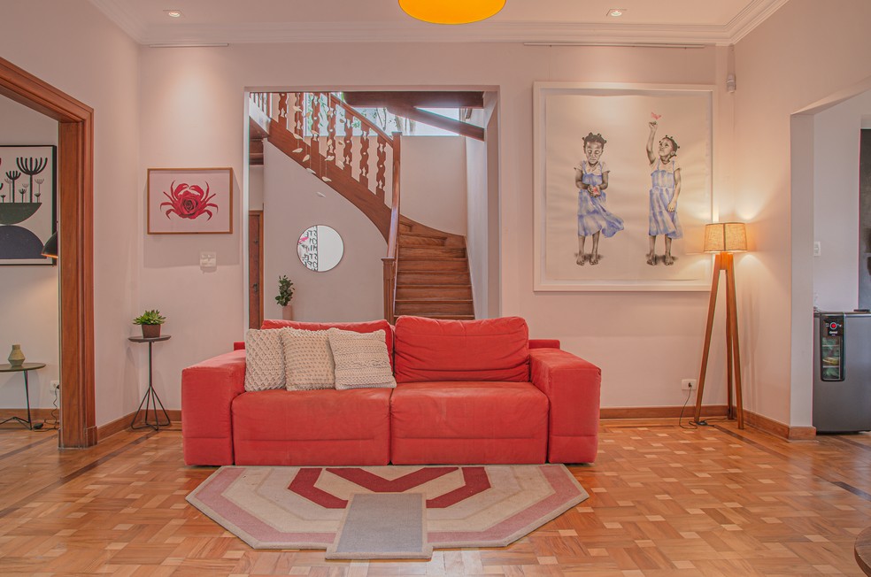 SALA | O sofá vermelho é o destaque da sala de estar. Móveis da Tok & Stok. Quadro da Urban Arts, feito pela artista sul africana Marié Stander — Foto: Lari Kennynsc / Divulgação