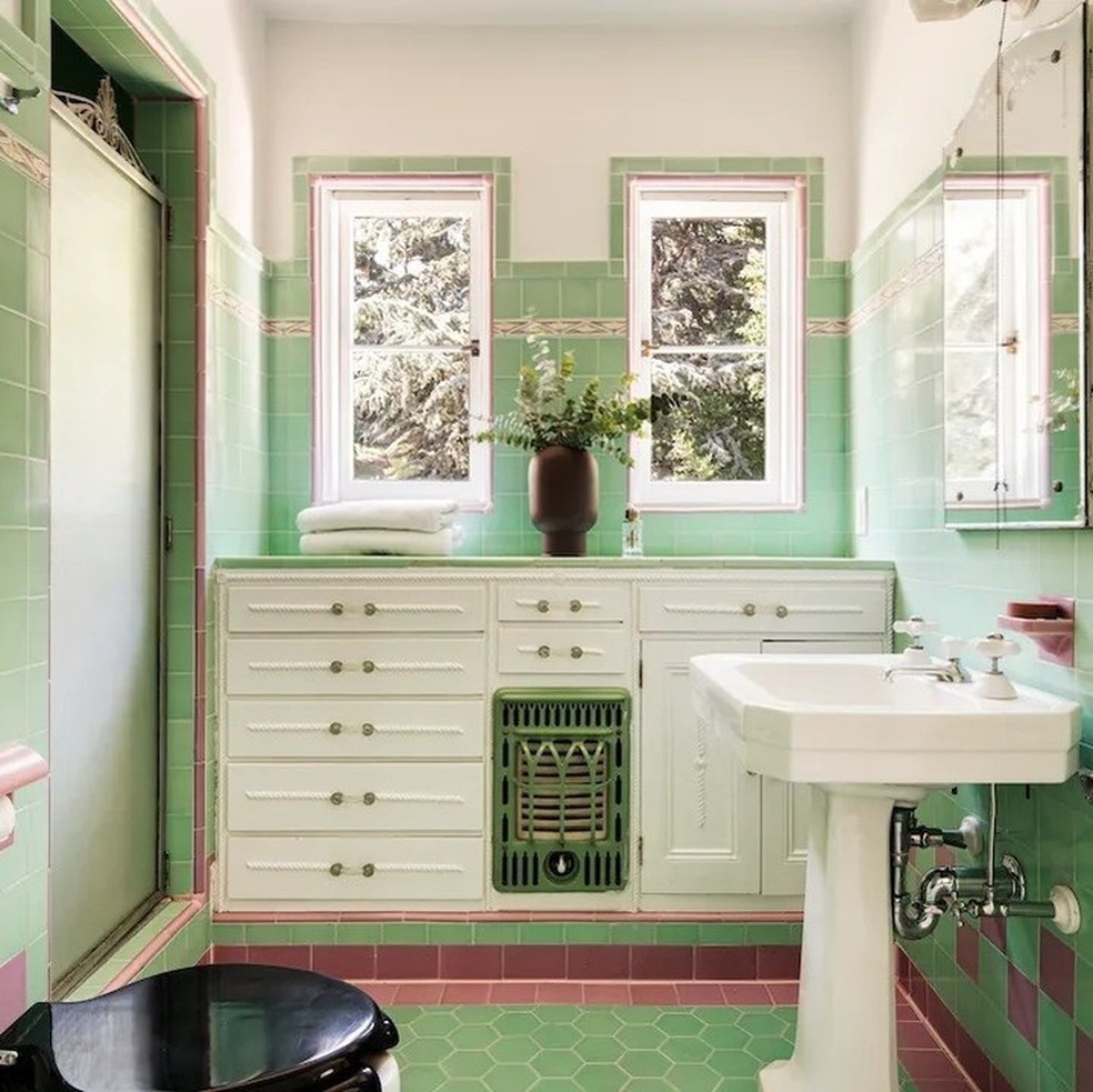 O banheiro tem paredes pintadas de verde e uma planta no centro de uma bancada — Foto: Robb Report / Instagram / Reprodução