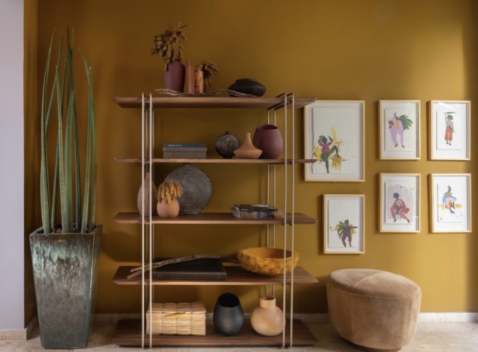 Enquanto as cerâmicas e as peças de artesanato estão expostas na estante, os quadros decoram a parede — Foto: Cacá Bratke / Divulgação