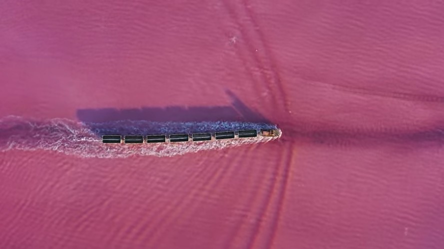 O lago rosa com um trem na água parece um cenário de mentira de tão surreal que é!