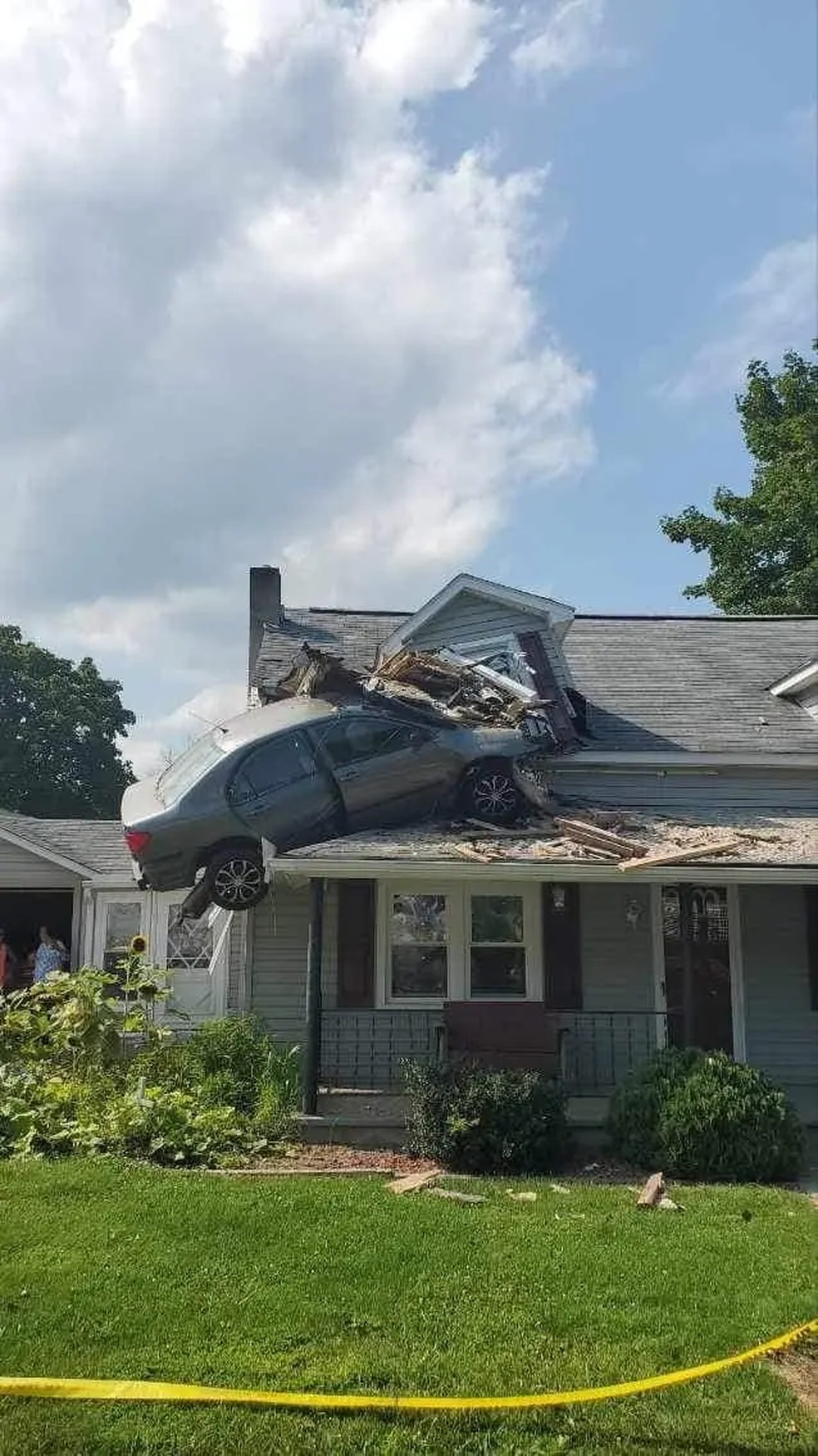 O Toyota Corolla ficou pendurado no segundo andar da casa depois de ser lançado sobre ela — Foto: Junction Fire Company / Divulgação