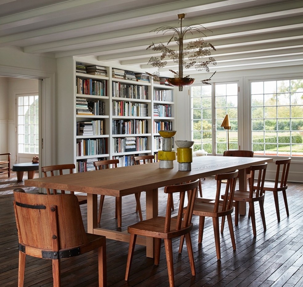 A sala de jantar tem uma mesa grande de oito lugares e estantes com diversos livros — Foto: Stephen Kent Johnson / OTTO / Reprodução