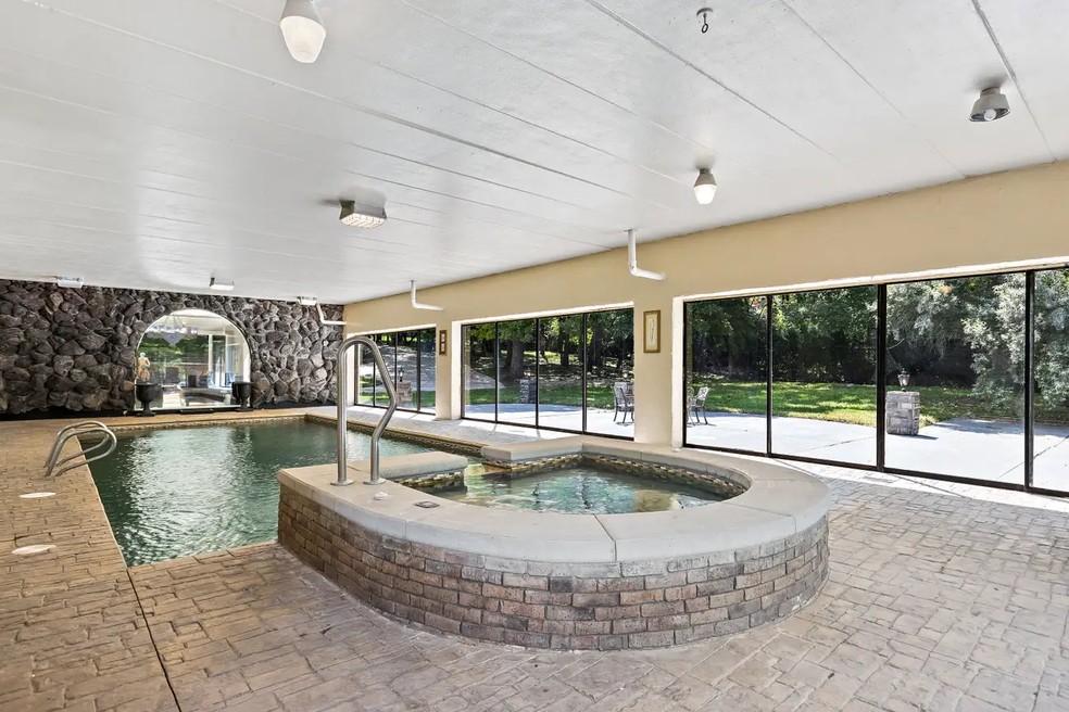 A piscina interior inclui uma banheira de hidromassagem e uma cascata — Foto: Rob Morrison / Coldwell Banker / Reprodução