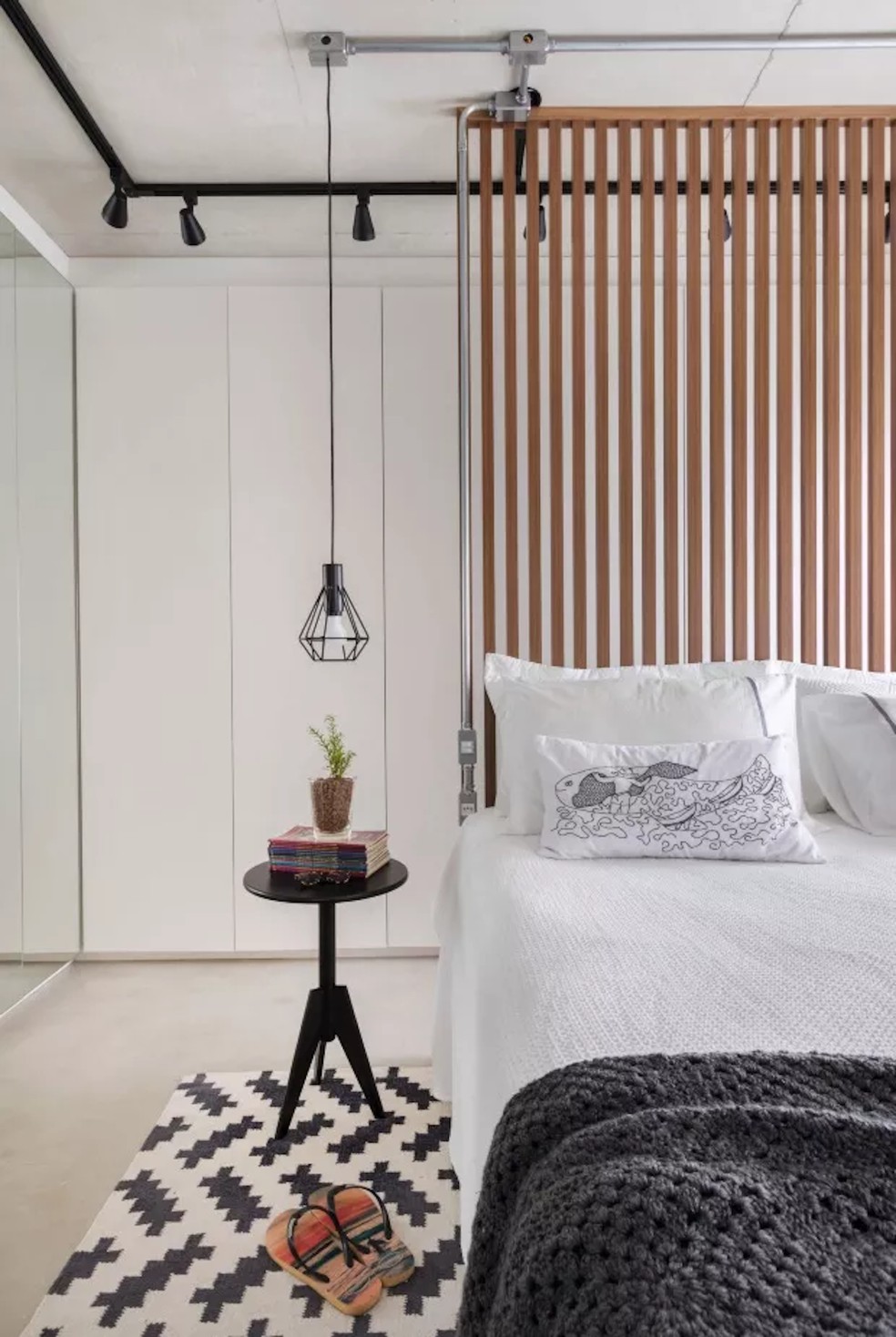 Um biombo de ripas de madeira serve de cabeceira e divide o quarto do closet. Projeto do SP Estúdio — Foto: Rafael Renzo / Divulgação