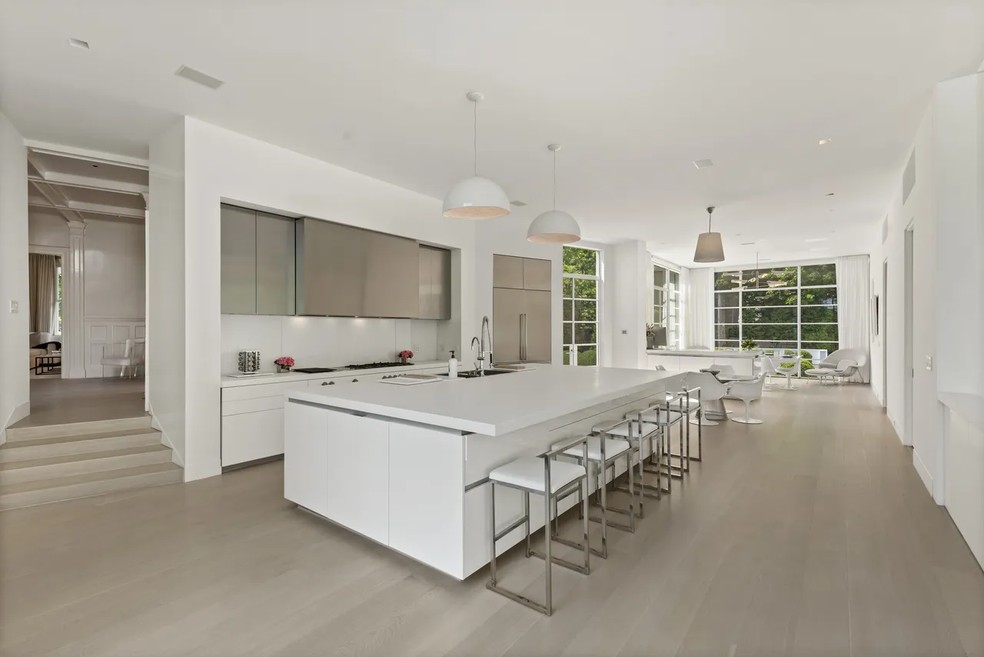 A cozinha possui uma grande bancada branca para refeições e preparos — Foto: Sotheby's International Realty / Realtor.com / Reprodução