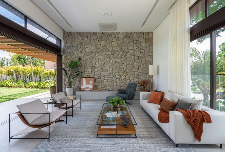 SALA | A parede de pedra moledo é o grande destaque do estar. Tapete é da Casa Frato e piso da Portobello