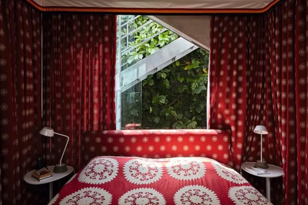A roupa de cama da suíte combina com as estampas vermelhas da parede — Foto: Victor Affaro / Editora Globo