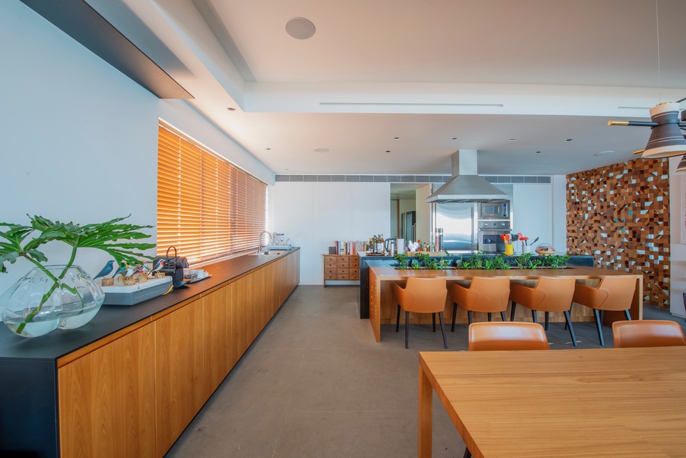 A ampla cozinha do apartamento traz uma mesa de almoço e ilha com banquetas — Foto: Top Rio / Divulgação
