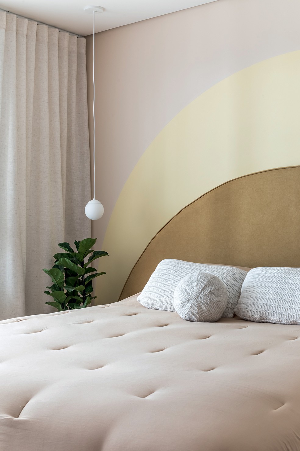 O quarto tem cabeceira de veludo que acompanha a forma arredondada da pintura da parede. Projeto do escritório OHMA Design — Foto: Eduardo Macarios / Divulgação