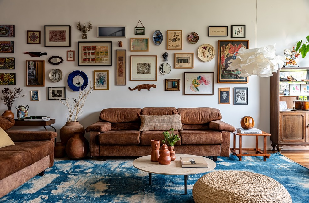 SALA | Almofada e pufe de palha da Codex Home, assim como a mesa de centro, com trio de vasos da Dpot Objeto. À esquerda, vasos de barro da Casa Atica. À direita, banco "Pequi", do designer Dan Azvdo para o Behavez Studio, da Deezign. Tapete azul da By Kamy — Foto: Wesley Diego / Divulgação
